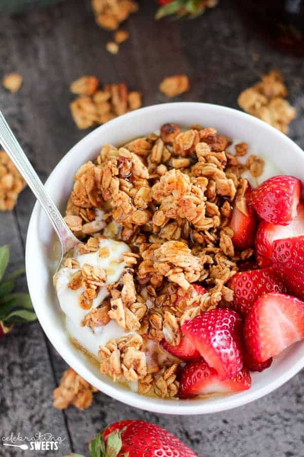 White bowl with granola, yogurt and strawberries.