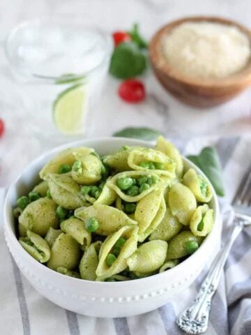 Bowl of pasta shells with pesto and peas.