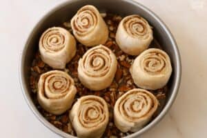 Unbaked sticky buns in a round pan.