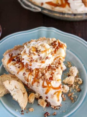 Slice of ice cream pie topped with caramel sauce and cookies.