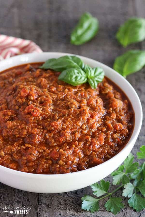 Meat sauce in a white bowl garnished with basil.