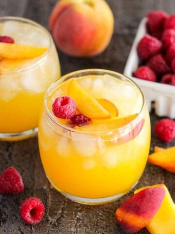 Peach margarita garnished with peaches and raspberries.