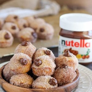 Bowl of donut holes filled with chocolate sauce coated in sugar.
