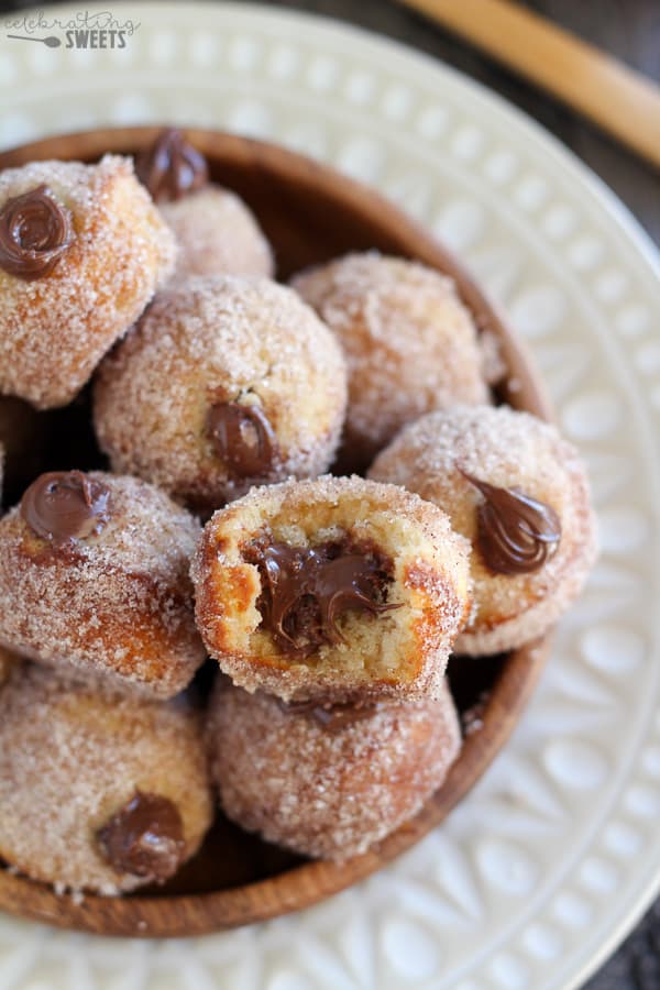 Bowl of donut holes filled with chocolate sauce coated in sugar.