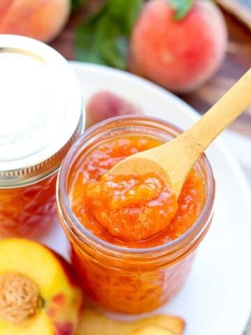 Closeup of peach jam with a wooden spoon.