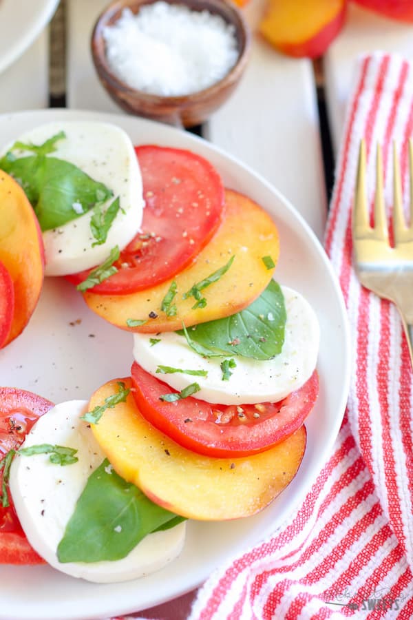 Sliced peaches, tomato, and mozzarella topped with basil.