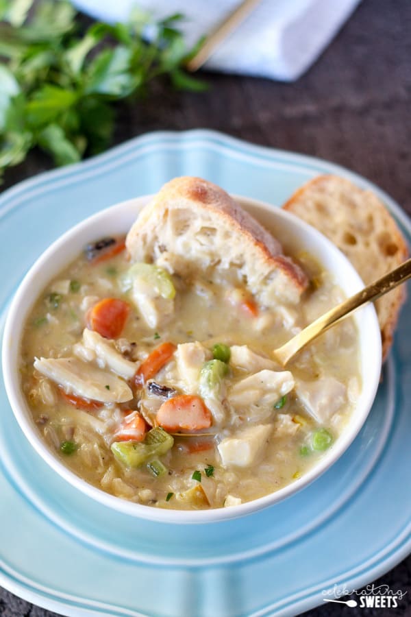A bowl of chicken rice soup with a piece of bread in it.