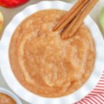 Applesauce in a white bowl with cinnamon sticks