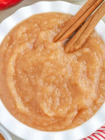 Applesauce in a white bowl with cinnamon sticks