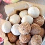 Bowl of apple cider donut holes topped with cinnamon sugar and icing.