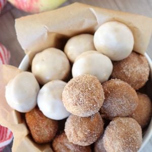 Bowl of apple cider donut holes topped with cinnamon sugar and icing.