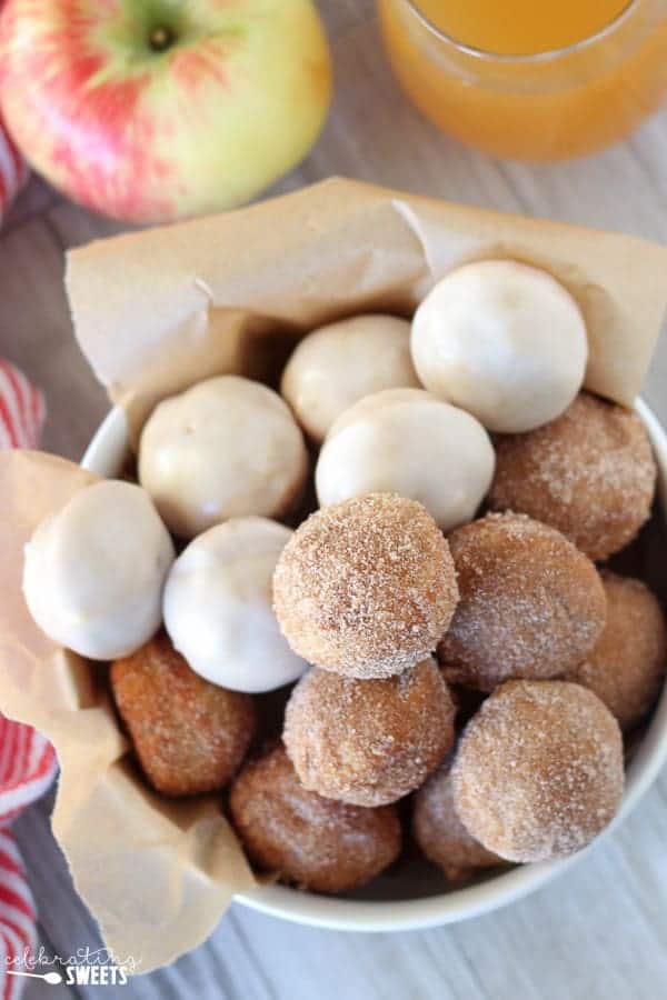 Bowl of apple cider donut holes topped with cinnamon sugar and icing.