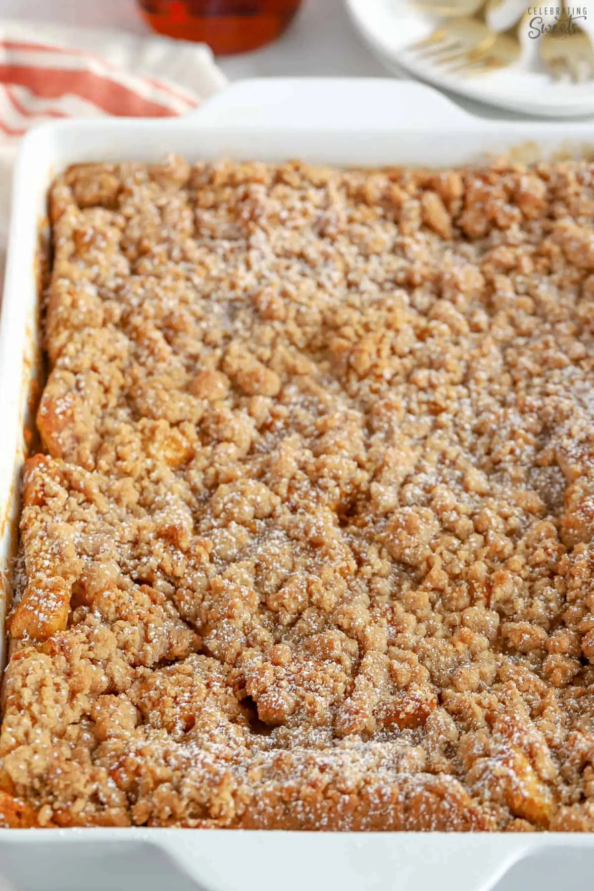 Pumpkin French toast casserole in a white baking dish topped with powdered sugar.