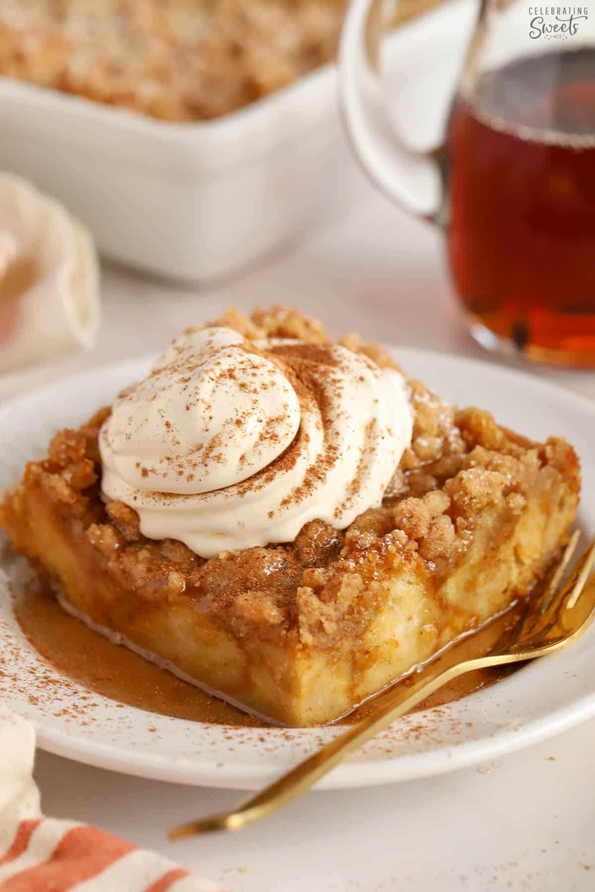 Pumpkin french toast casserole on a white plate topped with whipped cream and cinnamon