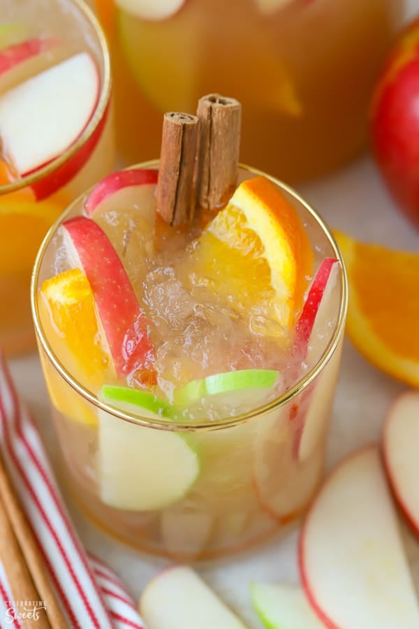 Sangria in a glass garnished with sliced apples, oranges, and cinnamon sticks. 