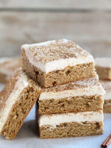 Stack of cookie bars topped with frosting and cinnamon sugar.