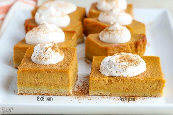 Pumpkin pie bars topped with whipped cream on a white plate.