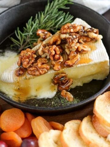Wedge of brie cheese topped with walnuts and honey.