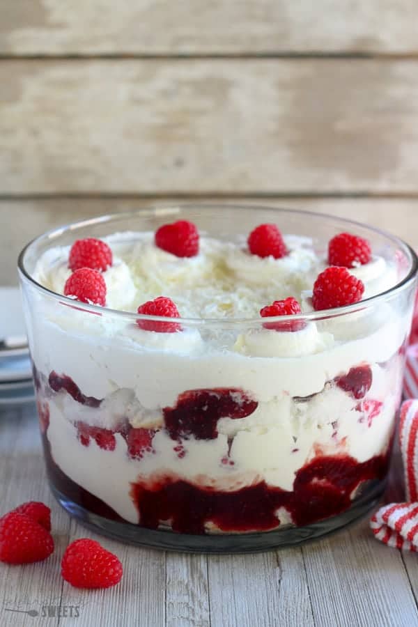 Trifle dish with cake, whipped cream, jam and raspberries.