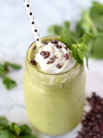 Mint chocolate chip smoothie in a glass topped with whipped cream.