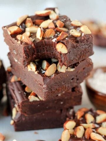 Stack of brownies topped with frosting and almonds.