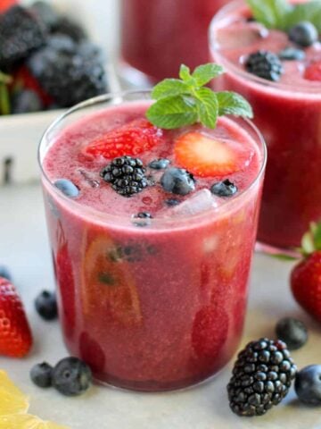 Glass of berry agua fresca topped with fresh berries and mint