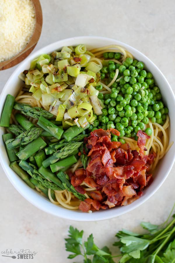Bowl of pasta with asparagus, peas, and bacon.