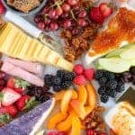 Marble board filled with fruit and cheeses.