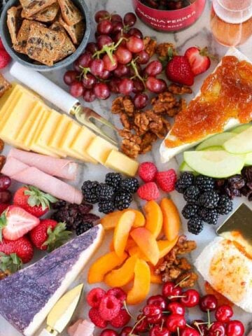 Marble board filled with fruit and cheeses.