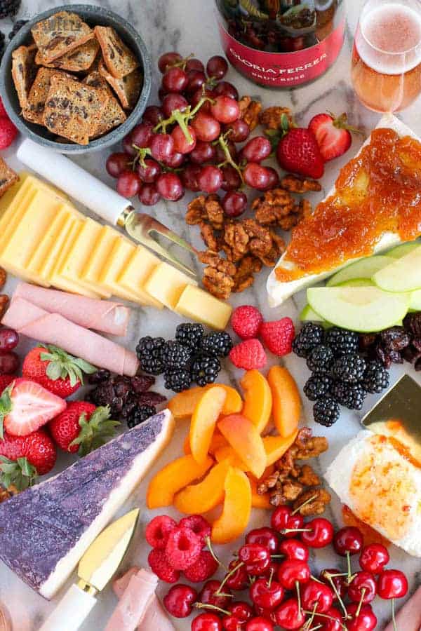 Marble board filled with fruit and cheeses.