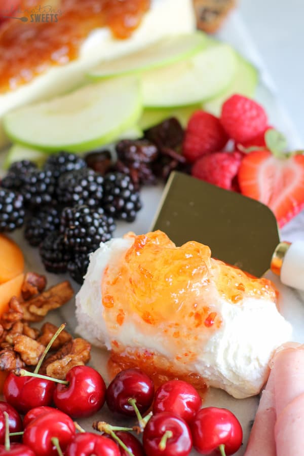 Marble board filled with fruit and cheeses.