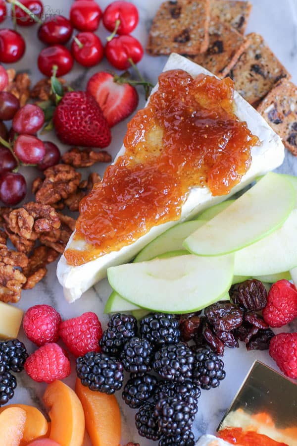 Marble board filled with fruit and cheeses.
