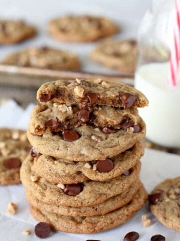 Stack of chocolate chip cookies with milk in the background.