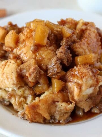 A serving of apple French toast casserole on a white plate with a gold fork.