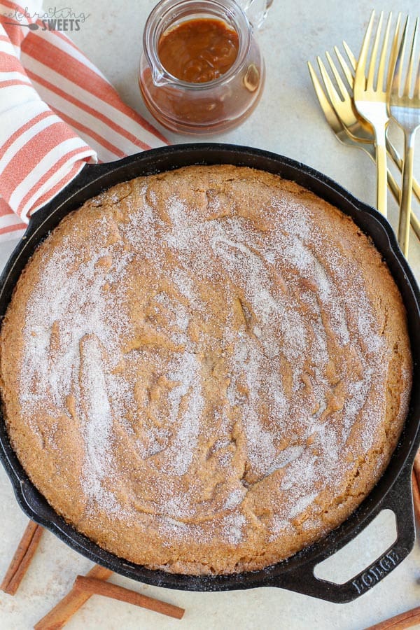 Large snickerdoodle cookie in a skillet topped with sugar.