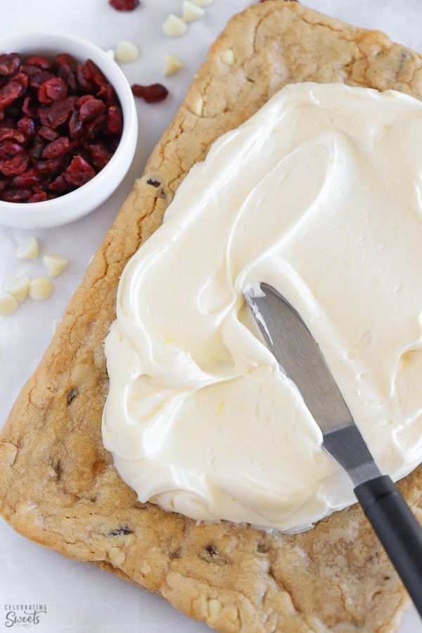 Frosting being spread onto blondie bars.