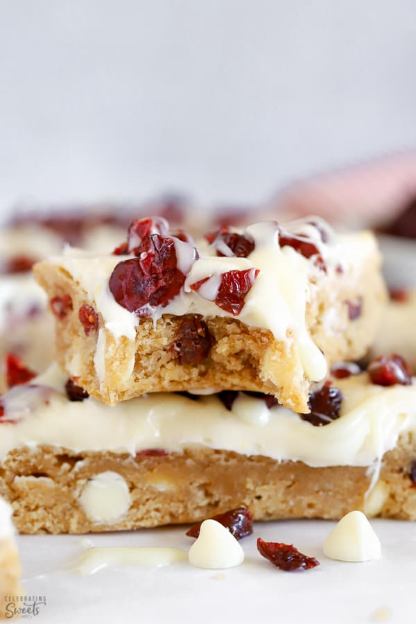 Two blondies topped with frosting and dried cranberries.