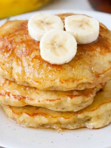 Stack of three banana pancakes on a white plate.