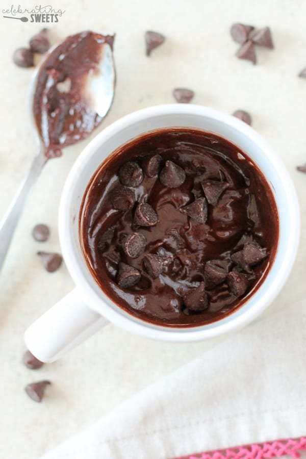 Brownie batter in white mug, topped with chocolate chips.