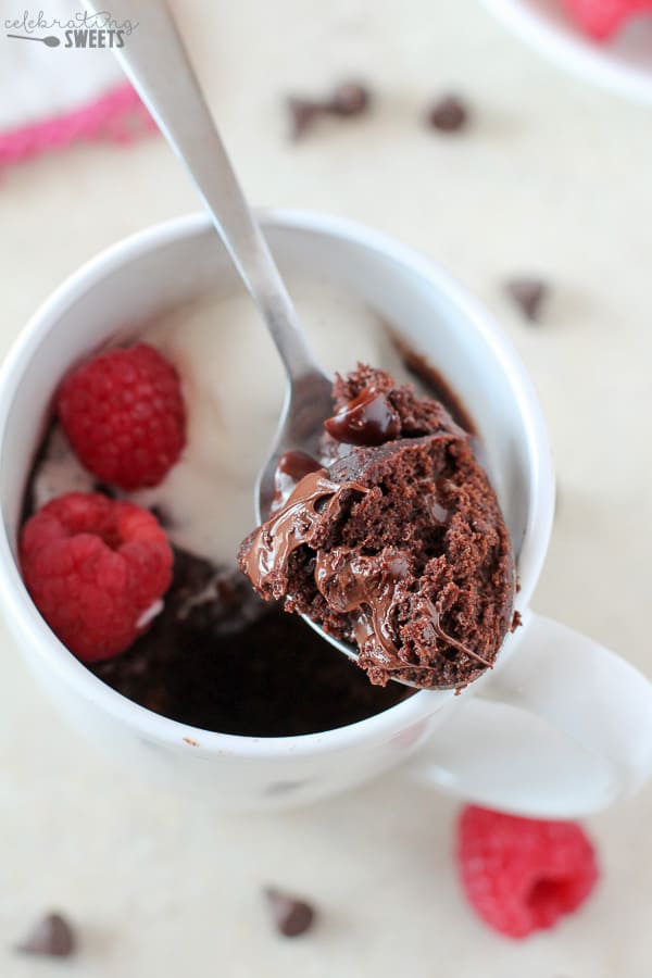 Spoonful of brownie on a silver spoon sitting on a white mug.