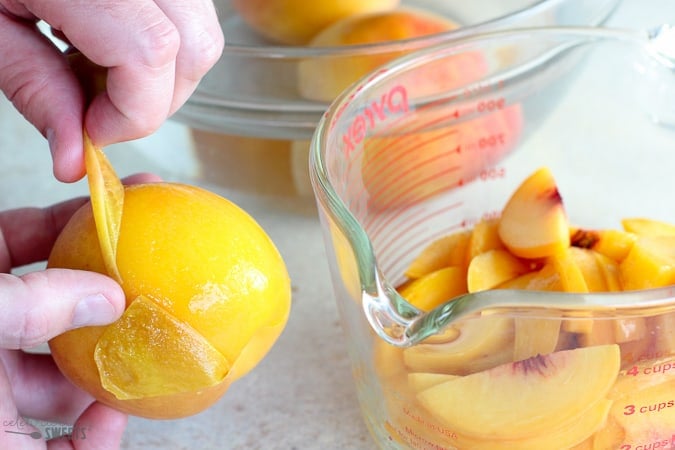 Peach skin being pulled off of a fresh peach.