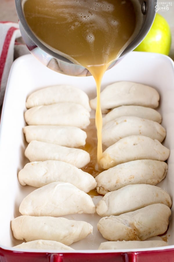 Sauce being poured over a dish filled with apple dumplings.
