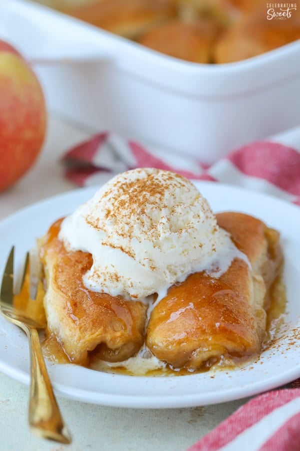 Two apple dumplings on a white plate topped with ice cream.