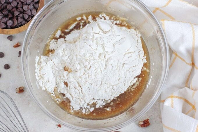 Flour on top of melted butter and sugar in a glass bowl.