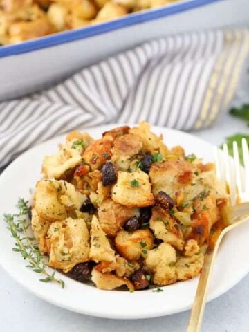 Fig and Sausage Stuffing on a white plate with a gold fork.