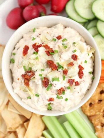 Sun dried tomato and artichoke dip in a white bowl.