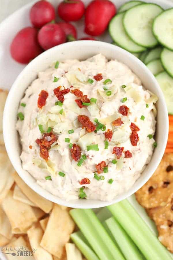 Sun dried tomato and artichoke dip in a white bowl. 