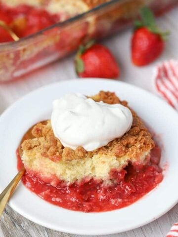 Strawberry Crumb Cake on a white plate with a dollop of whipped cream.