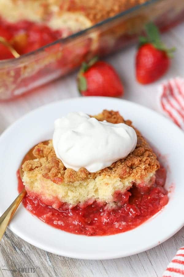 Strawberry Crumb Cake on a white plate with a dollop of whipped cream.