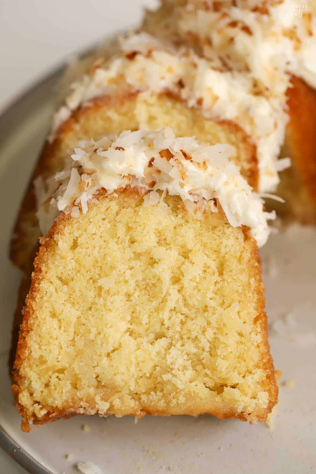 Slices of coconut bundt cake layered on a grey plate,